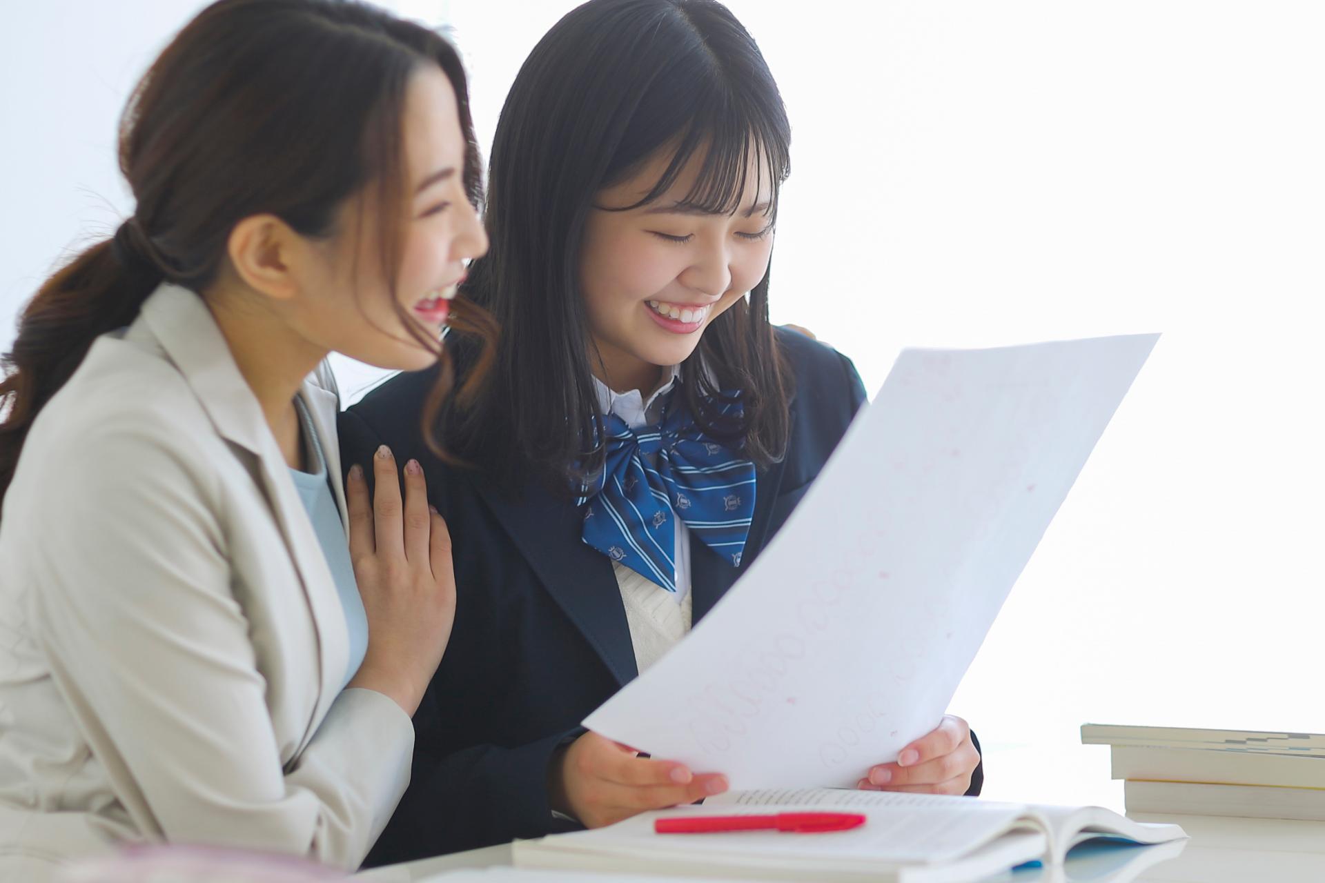 先生と生徒がテストの結果を見て喜んでいる様子